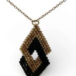 Κολιέ Miyuki Peyote σε μαύρο και χρυσό, με γεωμετρικό μοτίβο από χάντρες Delica και λεπτή χρυσή αλυσίδα.