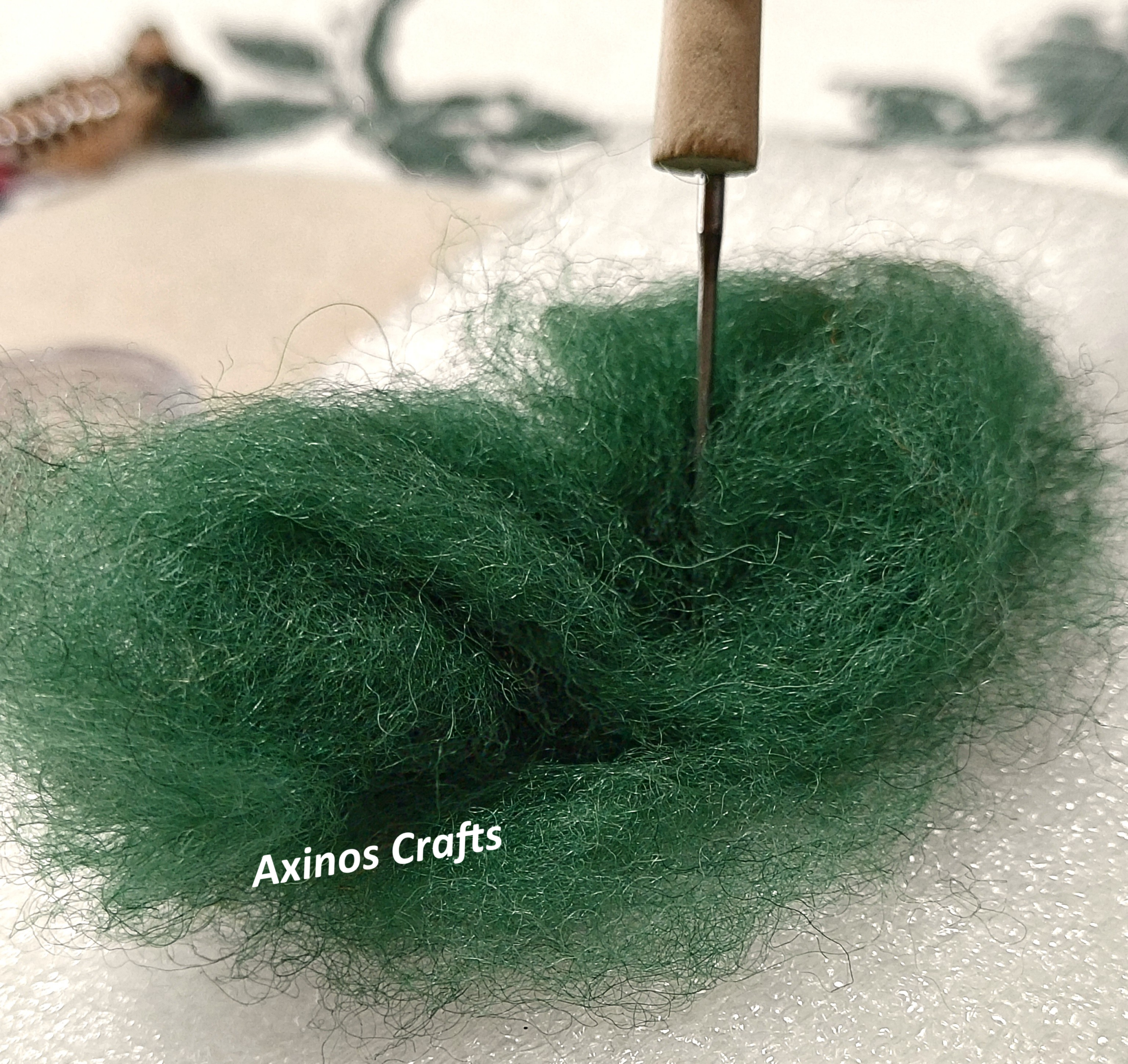 Κοντινή απεικόνιση της διαδικασίας needle felting, καθώς η ειδική βελόνα διαπερνά το φελτ και δουλεύει τις ίνες του υλικού.